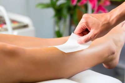 Young woman in Spa getting legs waxed for hair removal